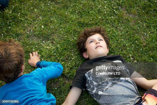 boy 10-11 years looking up, lying on grass - 10 11 years boy stock pictures, royalty-free photos & images