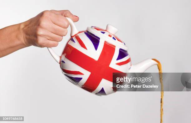 woman pouring tea from union jack teapot - blue teapot stock pictures, royalty-free photos & images