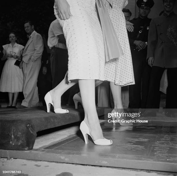 American actresses Marilyn Monroe and Jane Russell make imprints of their feet in wet cement in a joint handprint ceremony at Grauman's Chinese...