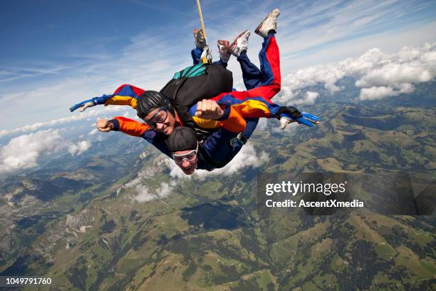 tandem-fallschirmspringer stürzen durch hohen himmel über berge - taking the plunge stock-fotos und bilder