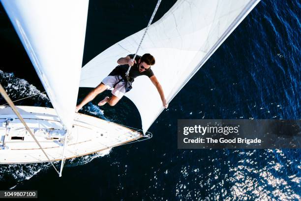 man on sailboat wearing safety harness - segeln stock-fotos und bilder