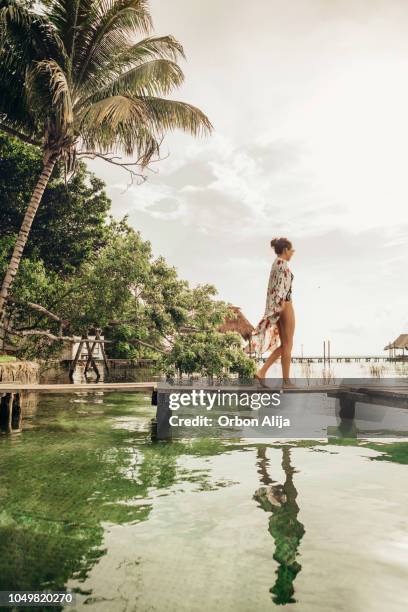 frau zu fuß auf einem pier an einer lagune - boho stock-fotos und bilder