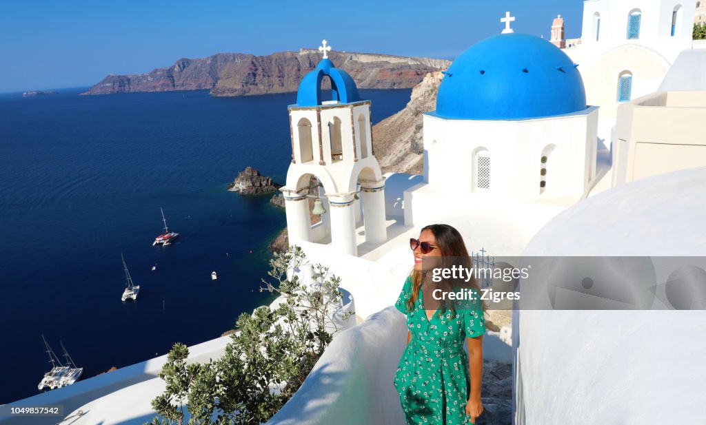 Mujer joven de pie junto a la iglesia en la montaña contra el cielo azul claro durante el día soleado