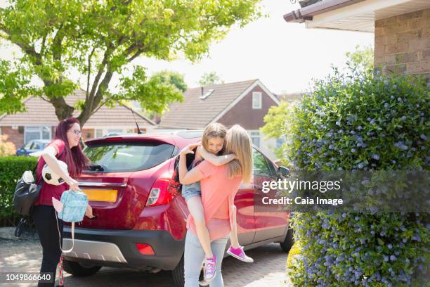 affectionate lesbian couple and daughter at car in sunny driveway - football wives and girlfriends - fotografias e filmes do acervo