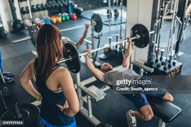 trainer showing exercise to a woman - bench press stock pictures, royalty-free photos & images