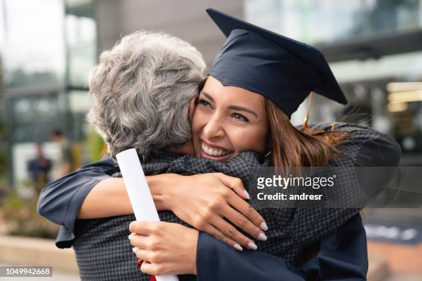 glückliche schüler ihr vater umarmt und feiern ihren abschluss - graduierten talar stock-fotos und bilder