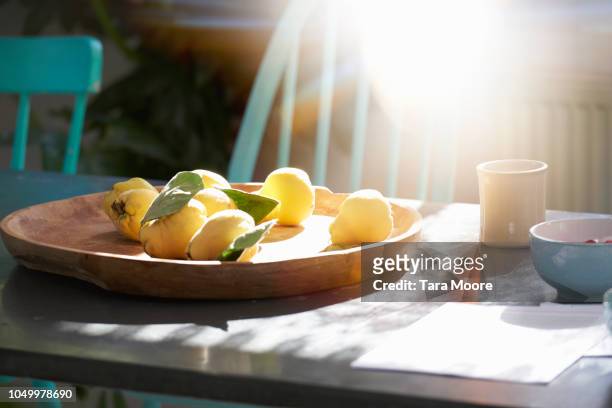 plate of quinces on plate in sunshine - kweepeer stockfoto's en -beelden