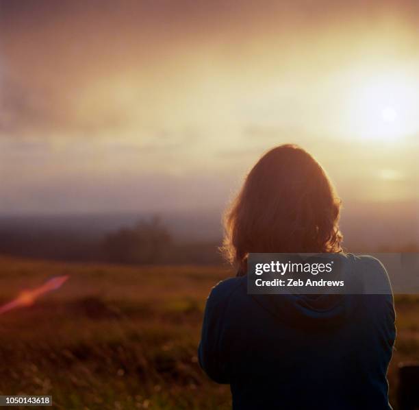 a young woman watches the sunset in hawaii - watching sunset stock pictures, royalty-free photos & images