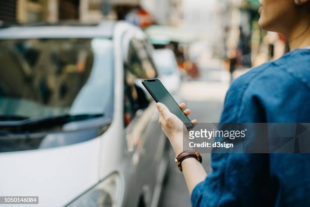 woman ordering a taxi ride with mobile app on smartphone in the city - electronic organizer stock pictures, royalty-free photos & images