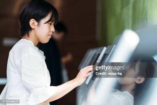 young woman using digital device at counter - digital store imagens e fotografias de stock