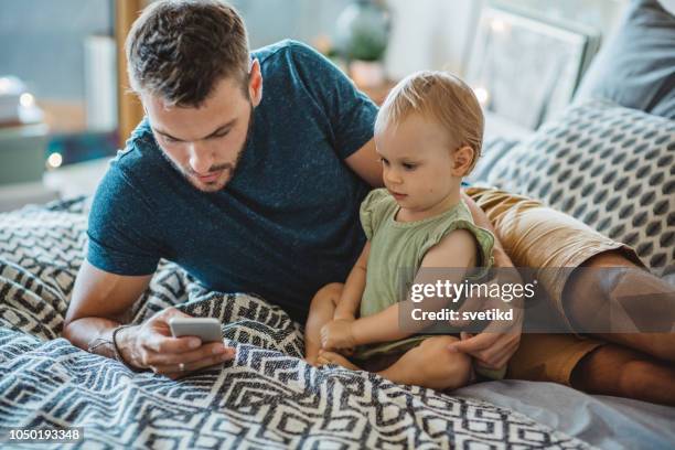 vader toont dochtertje iets op telefoon - baby pullover stockfoto's en -beelden