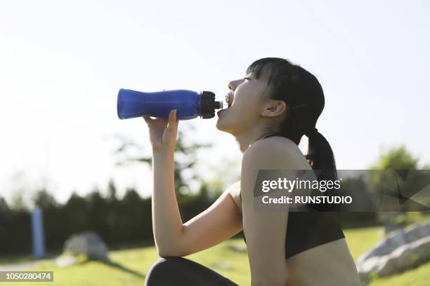 young woman drinking water in park - running refreshment stock pictures, royalty-free photos & images