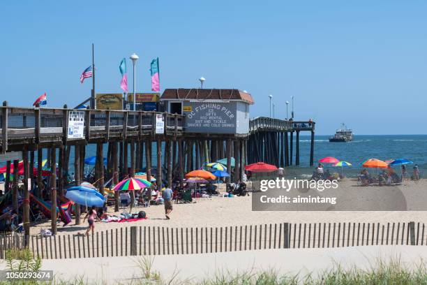 people enjoy their time on beach by fishing pier at ocean city - ocean city maryland stock pictures, royalty-free photos & images