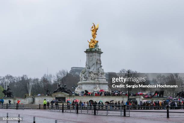 tourists standing in the rain in front of buckingham palace and the victoria memorial - london, england - the mall london stock pictures, royalty-free photos & images