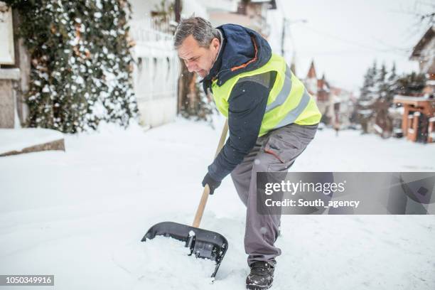 man cleaning snow on the street - older man snow shovel stock pictures, royalty-free photos & images