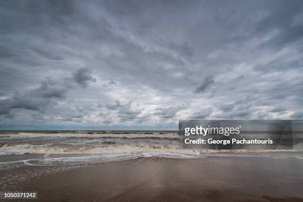 dramatic clouds on a beach - wasserrand stock-fotos und bilder