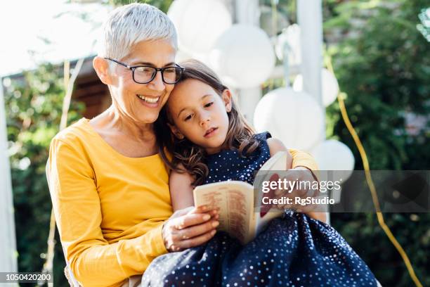 senior woman reading to granddaughter - kids reading glasses stock pictures, royalty-free photos & images