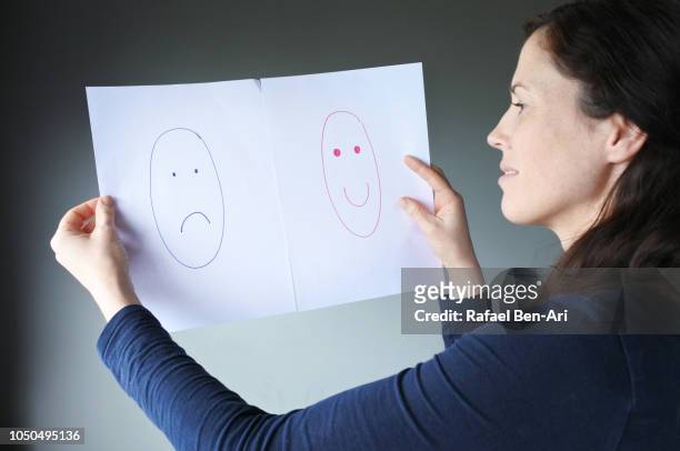 mature adult woman choosing between happiness and sadness - hypocrisy stock pictures, royalty-free photos & images