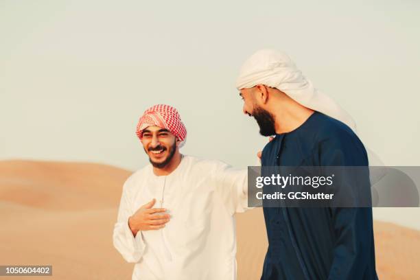 two middle eastern friends having a conversation in the desert. - oman family stock pictures, royalty-free photos & images
