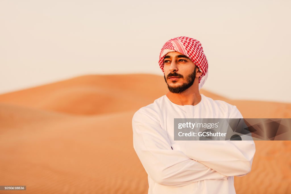 Middle eastern man standing armscrossed while admiring the sand dunes