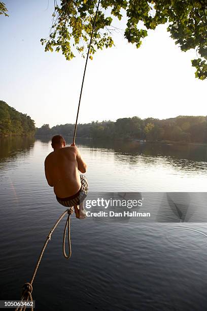 man on rope swing - rope swing fotografías e imágenes de stock