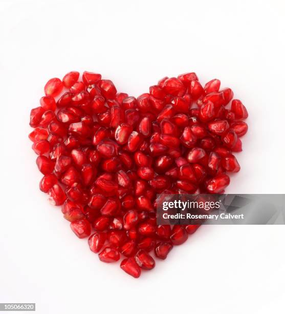 pomegranate seeds arrange to create a heart shape. - granaatappel stockfoto's en -beelden