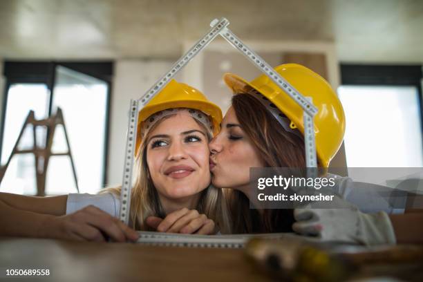 young female worker kissing her colleague during home renovation process. - house rules stock pictures, royalty-free photos & images