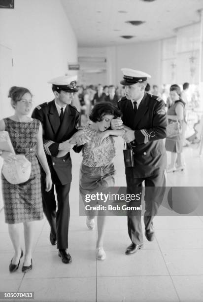 Pair of security guards half carry and half walk a woozy young woman along a corridor in the Deauville Hotel after she saw the Beatles, Miami Beach,...