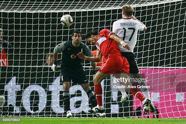 Per Mertesacker of Germany tries to score against Servet Cetin and goalkeeper Volkan Demirel of Turkey during the EURO 2012 group A qualifier match...