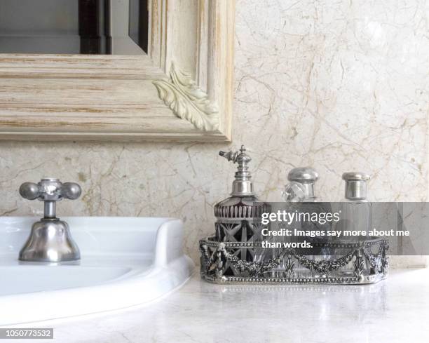 a silver tray with a collection of antique perfume bottles over a bathroom counter. still life. - bathroom sink stock pictures, royalty-free photos & images