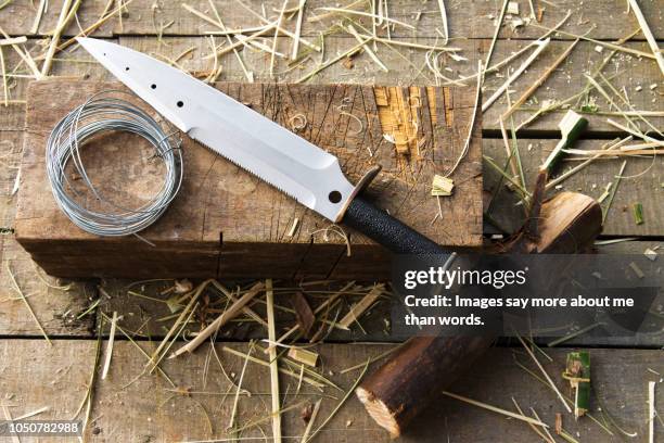 a survival knife with a wire roll over a wood block. still life. - knife block stock-fotos und bilder