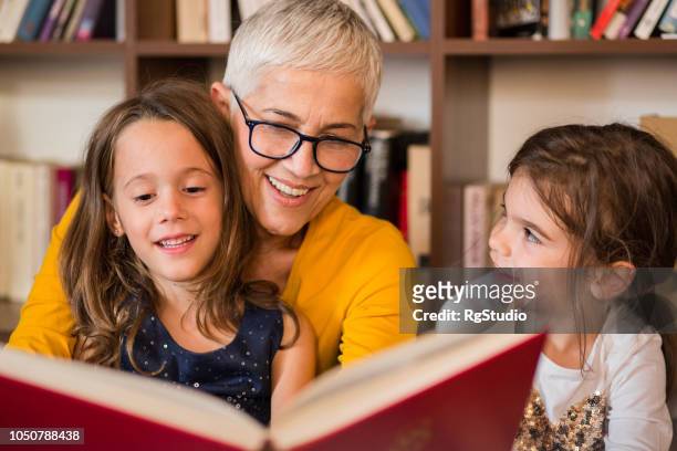 oude vrouw aflezing en kleindochters - kids reading stockfoto's en -beelden