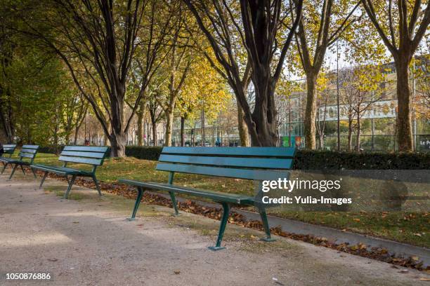 empty blue benches in park during autumn  paris  france - park bench stock-fotos und bilder