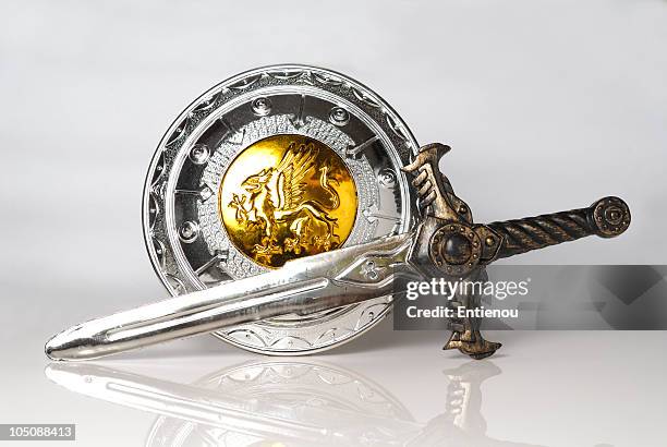 silver and gold shield and sword against white background - sword bildbanksfoton och bilder