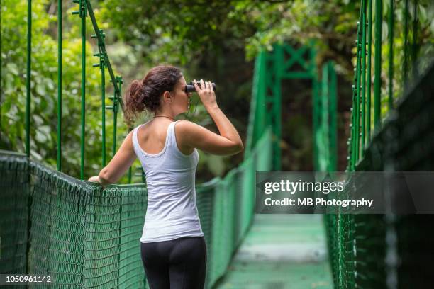 woman on hanging bridge with binoculars - モンテベルデ雲林保護区 ストックフォトと画像