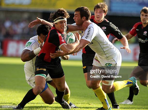 Derick Hougaard of Saracens is tackled by Alexandre Lapandry and Napolioni Nalaga during the Heineken Cup match between ASM Clermont Auvergne and...