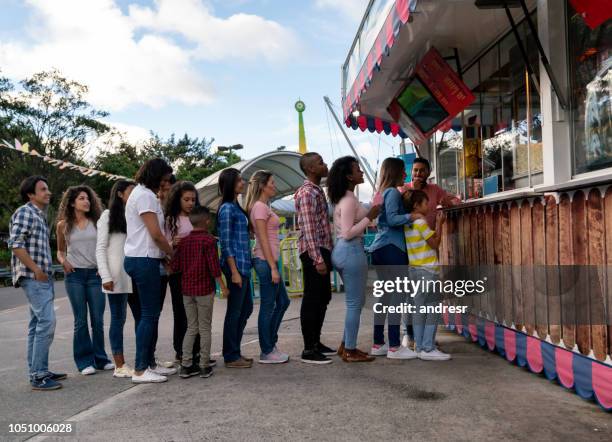 persone felici che acquistano cibo in un parco divertimenti - in fila foto e immagini stock