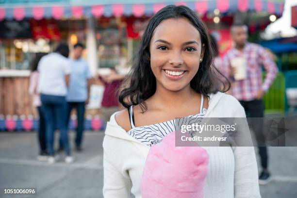 happy girl eating a cotton candy at an amusement park - colombia festival stock pictures, royalty-free photos & images