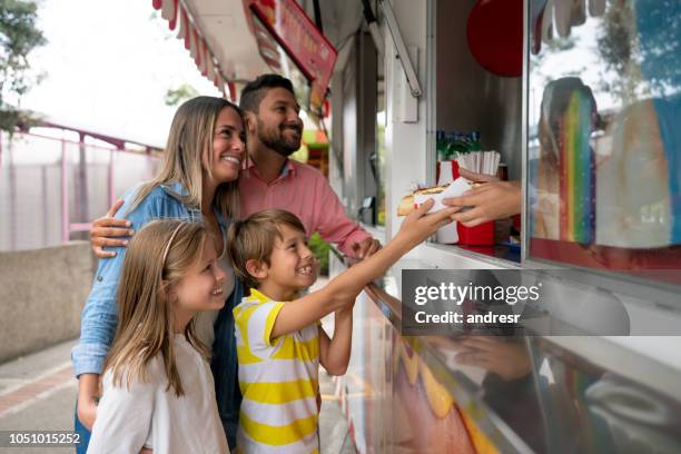 het kopen van voedsel op een pretpark en gelukkige familie - food stall stockfoto's en -beelden