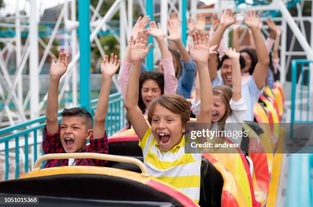 gelukkig groep mensen met plezier in een rollercoaster aan een pretpark - amusement park ride stockfoto's en -beelden