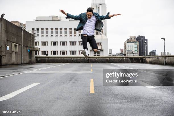 asiatischer mann in urban exploration auf den dächern der stadt - hip hopper stock-fotos und bilder