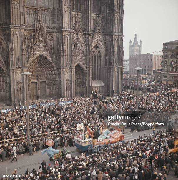 View of crowds of spectators watching a cavalcade of floats taking part in a Rosenmontag day carnival procession past the main entrance of Cologne...