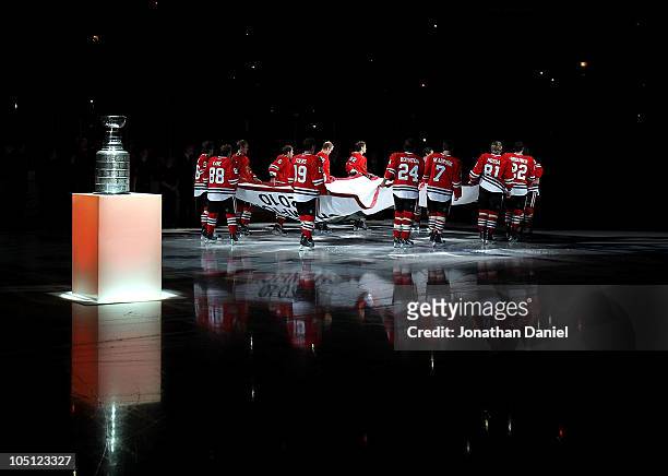 Members of the Chicago Blackhawks carry the Stanley Cup Championship banner across the ice past the Stanley Cup in a ceremony before the Blackhawks...