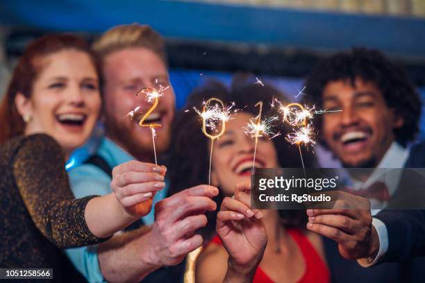 lächelnde menschen halten wunderkerzen - new years eve 2019 stock-fotos und bilder