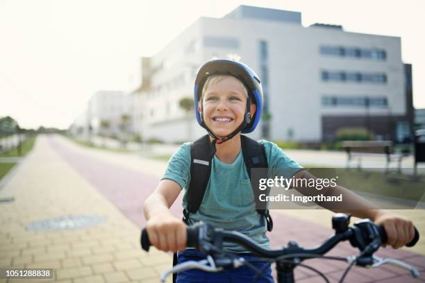 happy little boy riding bicycle in modern residential area - cycling helmet stock pictures, royalty-free photos & images