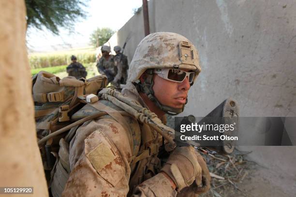 Marine LCpl. Jorge Serrano of Houston, TX attached to India Battery, 3rd Battalion, 12th Marine Regiment takes cover outside a compound during a...