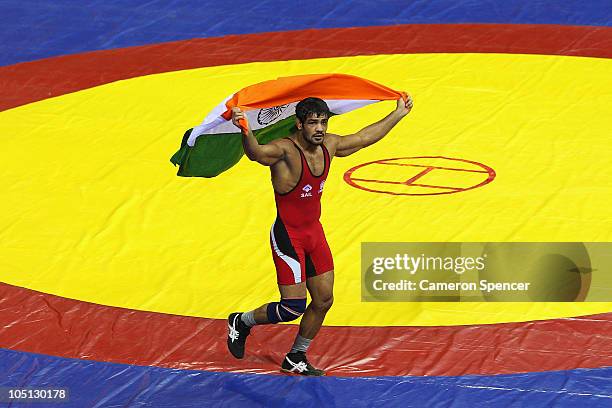 Sushil Kumar of India runs a lap of honour after winning against Heinrich Barnes of South Africa in the men's 66kg freestyle gold medal wrestling at...
