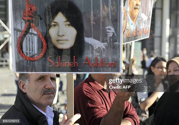 Person holds a placard showing a portrait of Iran's Sakineh Mohammadi-Ashtiani , who has been sentenced to death by stoning for adultery, as he...