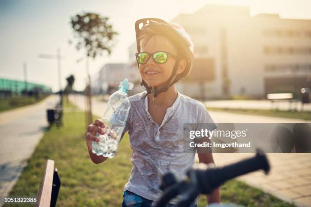 little boy riding bicycle and drinking water - boy drinking water stock pictures, royalty-free photos & images