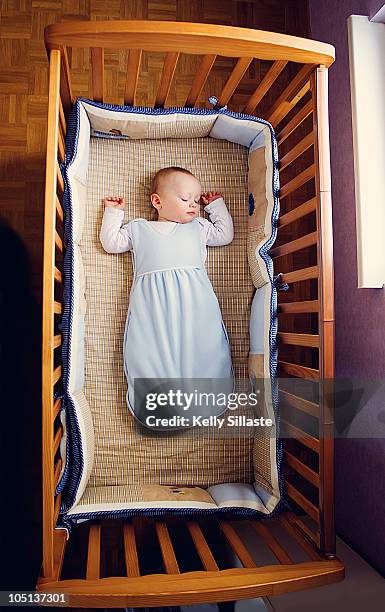 baby boy sleeping peacefully in crib - saco de dormir fotografías e imágenes de stock